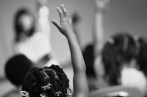 children in class with raised hands