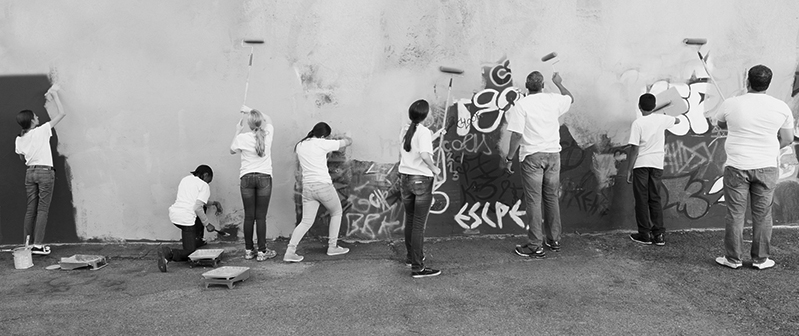 Volunteers painting over graffiti wall