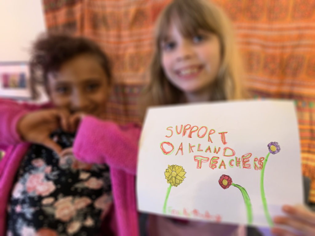 two students holding a sign that reads "support Oakland teachers"