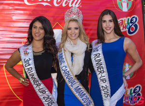 beauty pageant contestants stand in front of a Coke-branded Calle Ocho sign