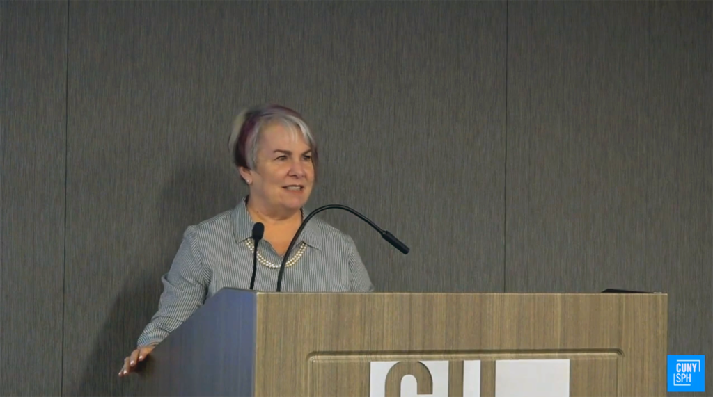 Lori Dorfman standing behind a lectern