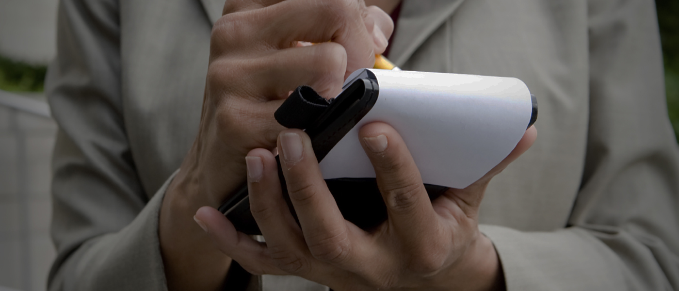 close-up of female reporter's hands, holding a pen and notepad.