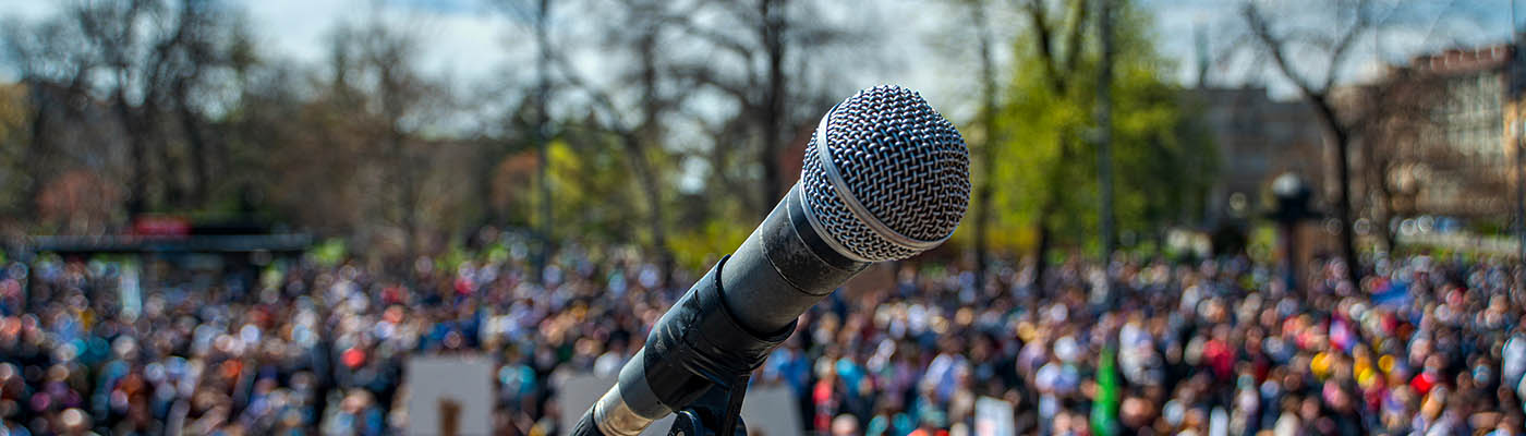 Microphone on a stage with blurry crowd in the background.