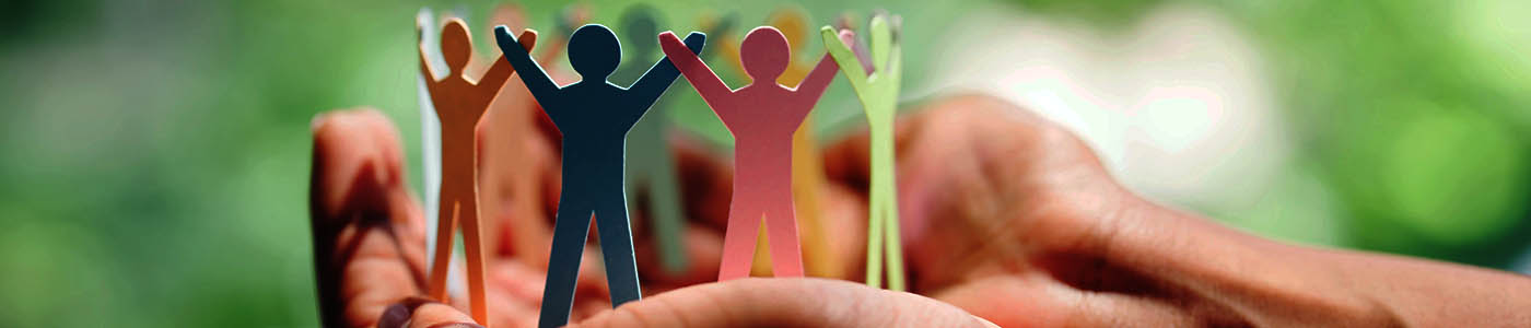 Cut-outs of multi-colored paper dolls resting inside a person's open palms.