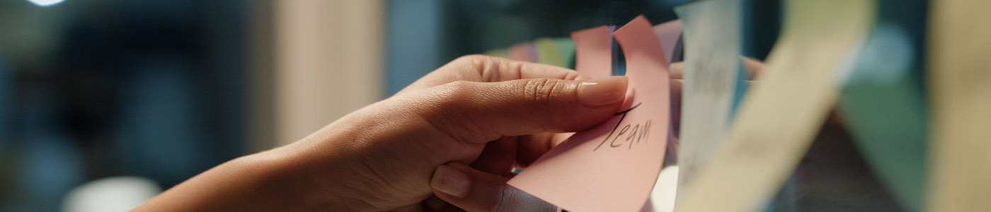 hand placing multi-colored sticky notes on a glass window