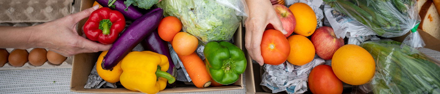 fresh produce on a table, with people's hands reaching for bell peppers and tomatoes
